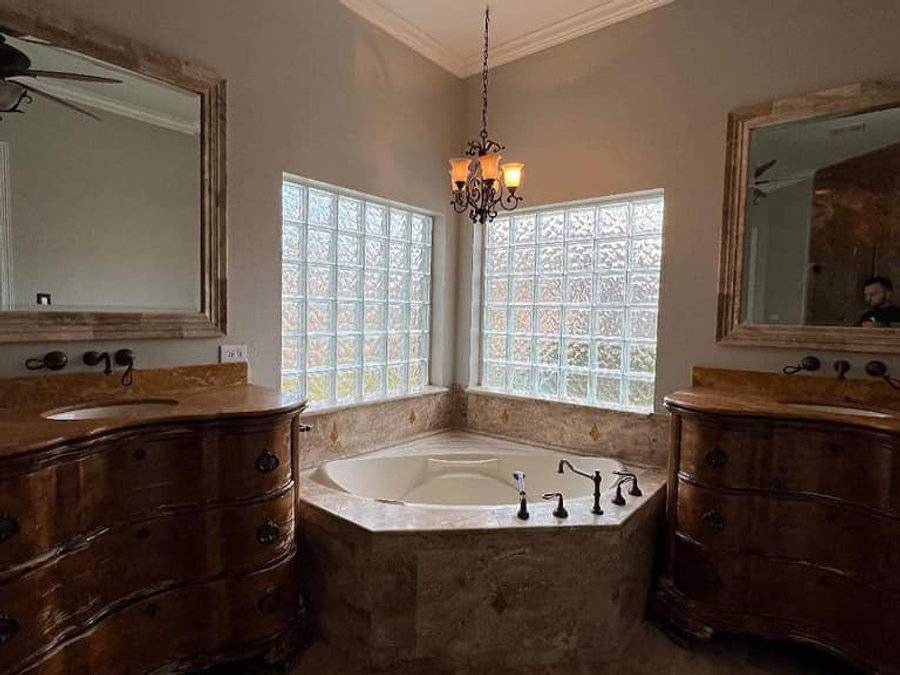 Primary bathroom before: dated corner garden tub and heavy wood vanities